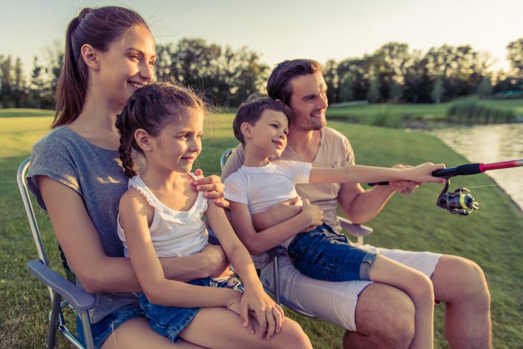 Beautiful happy family is smiling while catching fish in the pond