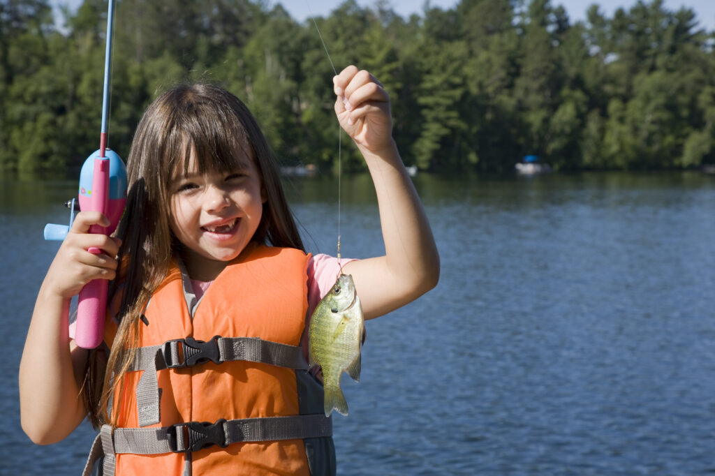 girl proudly holding bluegill she caught fishing
